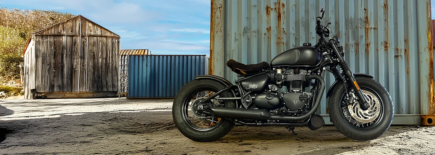 Triumph Bonneville Bobber Black in mattschwarzer Ausführung, seitliche Ansicht mit 1200-ccm-Parallel-Twin und schwarzer Doppelscheibenbremse, fotografiert in der Nähe von MotoPassion in Emmering bei München.