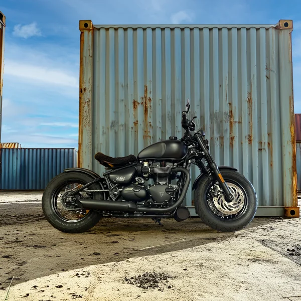 Triumph Bonneville Bobber Black in mattschwarzer Ausführung, seitliche Ansicht mit 1200-ccm-Parallel-Twin und schwarzer Doppelscheibenbremse, fotografiert in der Nähe von MotoPassion in Emmering bei München.
